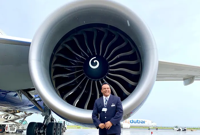 Sabbir Karim in British Airways uniform beside an aircraft engine