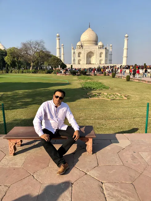Sabbir Karim sitting on a bench in the gardens of the Taj Mahal