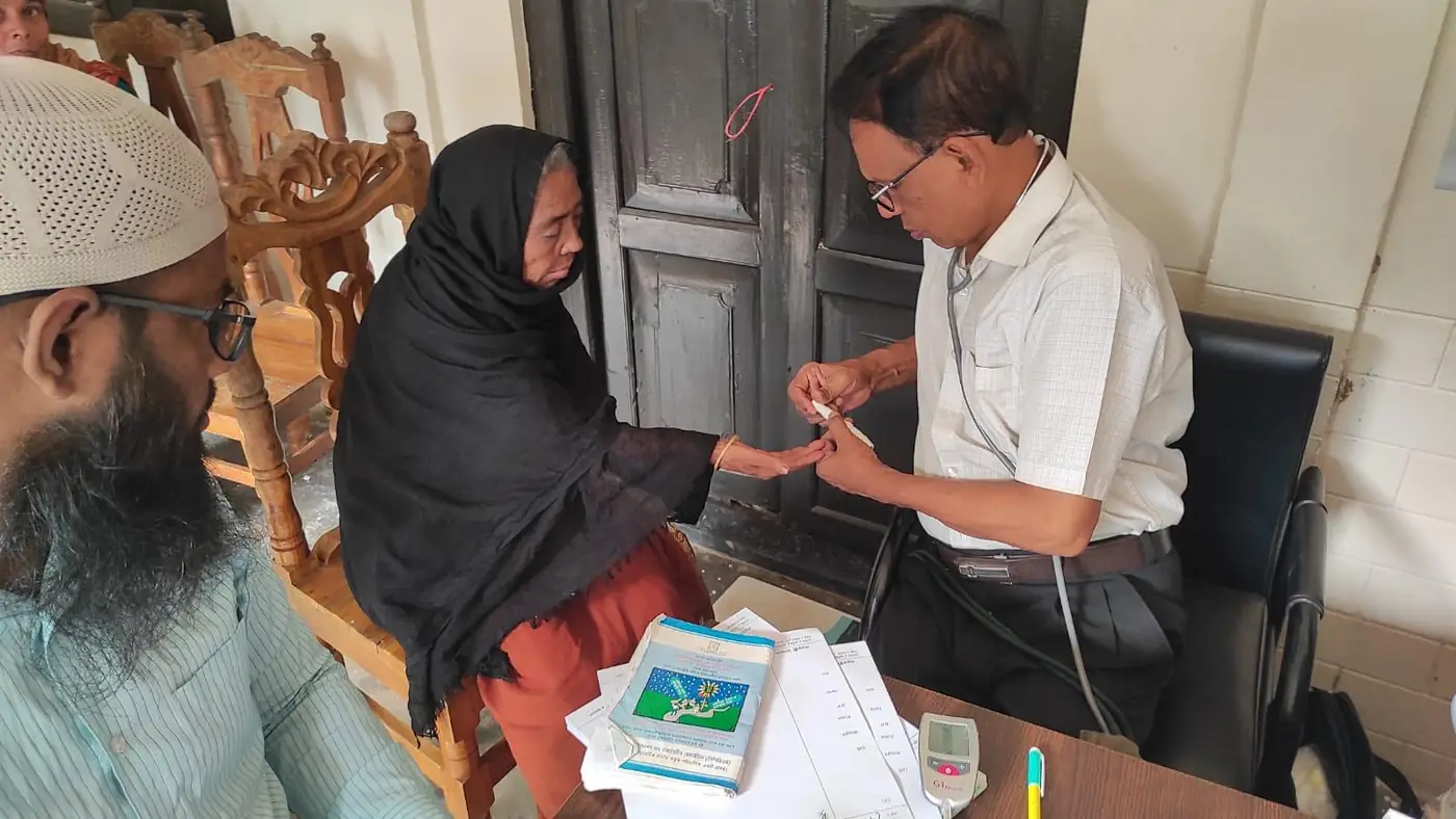 A doctor checking a patient’s blood sugar at a free clinic in Bangladesh