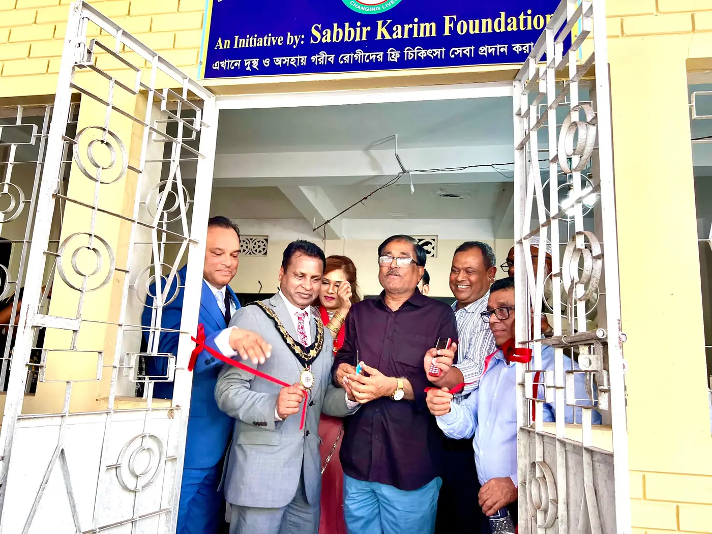 Sabbir Karim and local dignitaries cutting a ribbon beneath a Sabbir Karim Foundation sign