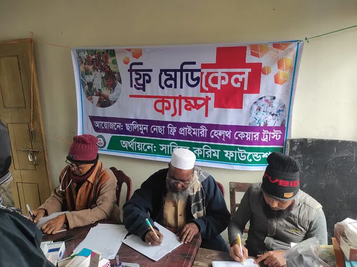 Doctors and volunteers at a free medical camp beneath a Bengali banner