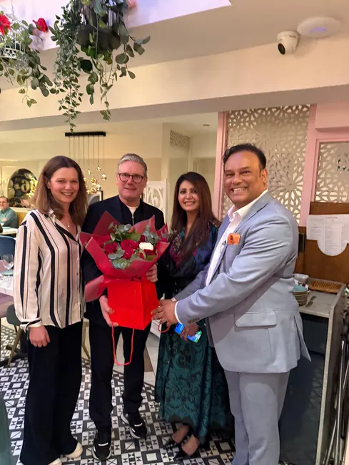 Sabbir Karim with guests holding a bouquet in the dining room